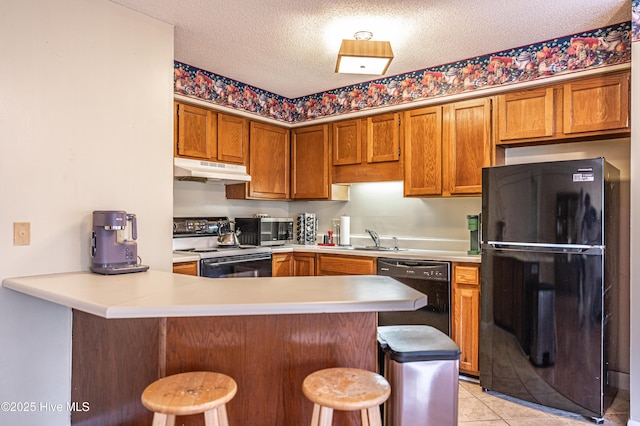 kitchen featuring black appliances, sink, a kitchen bar, kitchen peninsula, and a textured ceiling