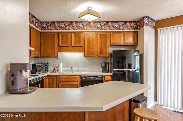 kitchen featuring sink, kitchen peninsula, a textured ceiling, and black appliances