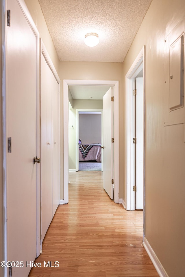 hall featuring light hardwood / wood-style flooring and a textured ceiling