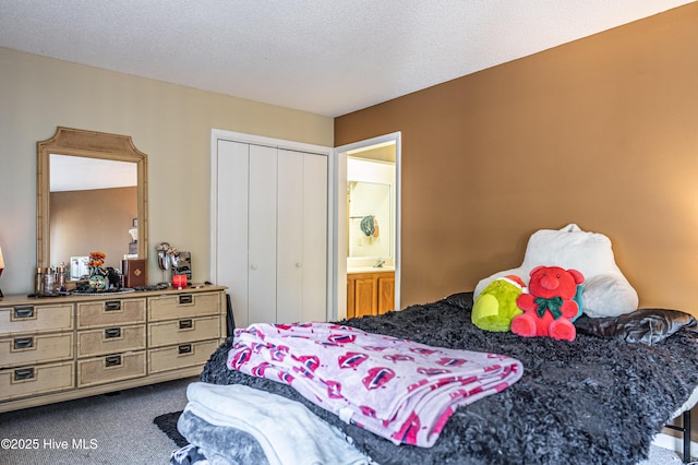 bedroom featuring carpet, ensuite bath, a textured ceiling, and a closet