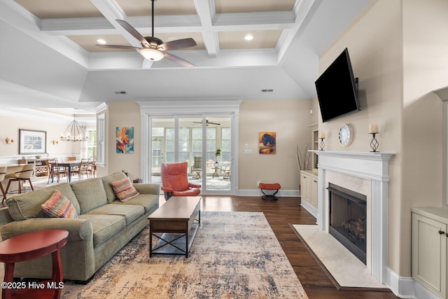 living room featuring ceiling fan with notable chandelier, dark hardwood / wood-style flooring, coffered ceiling, a high end fireplace, and beam ceiling