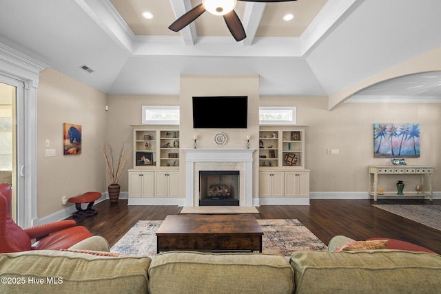 living room featuring dark hardwood / wood-style floors, ceiling fan, a high end fireplace, crown molding, and beam ceiling