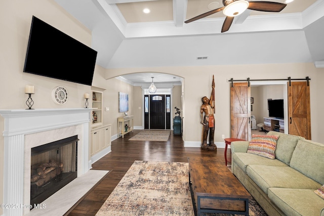 living room with beamed ceiling, ornamental molding, coffered ceiling, a barn door, and dark wood-type flooring