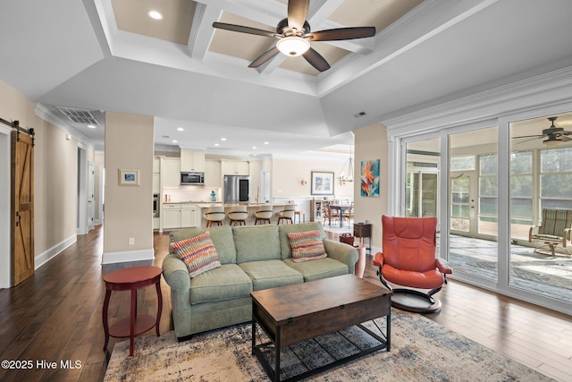 living room with ceiling fan, hardwood / wood-style floors, coffered ceiling, ornamental molding, and a barn door