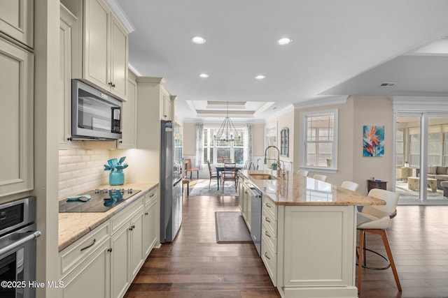 kitchen featuring sink, a breakfast bar, a kitchen island with sink, stainless steel appliances, and light stone counters