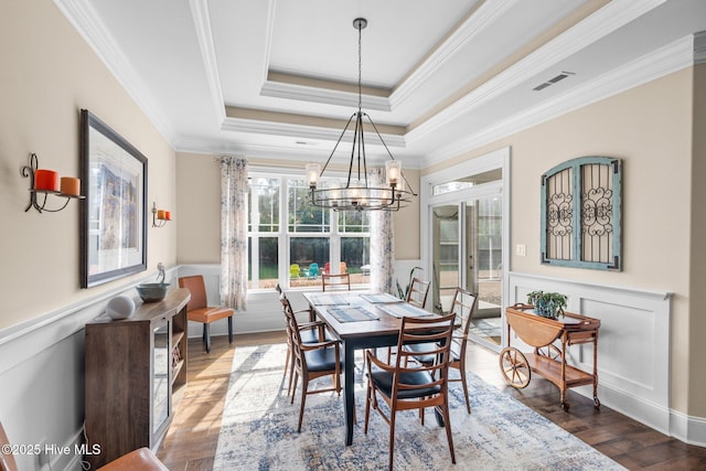 dining space with crown molding, hardwood / wood-style floors, a chandelier, and a tray ceiling