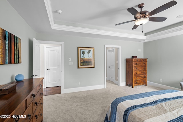 bedroom with a raised ceiling, light carpet, and ceiling fan