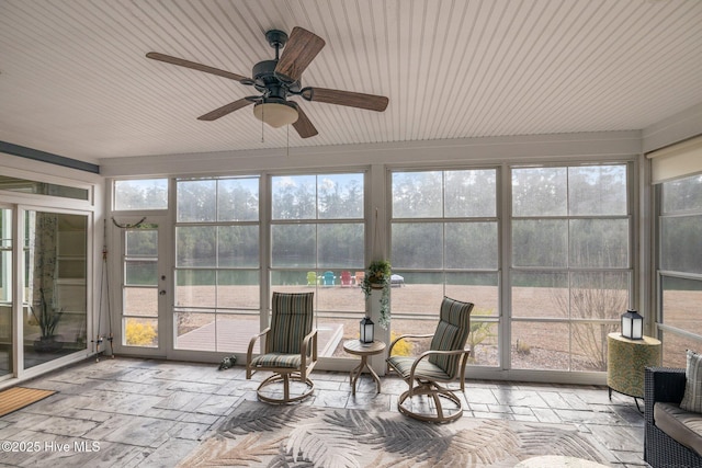 sunroom featuring a water view and ceiling fan