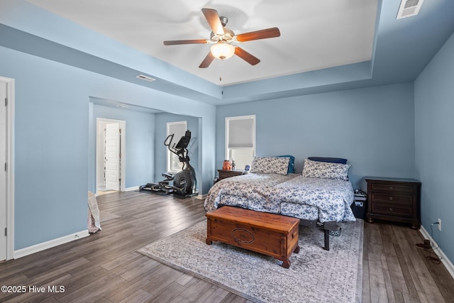 bedroom featuring ceiling fan, a tray ceiling, and dark hardwood / wood-style flooring