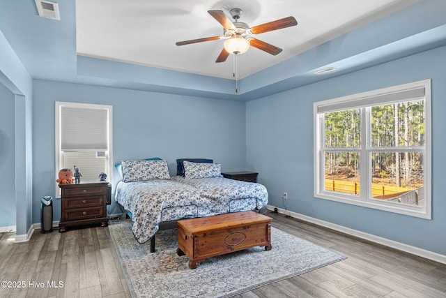 bedroom featuring hardwood / wood-style floors, ceiling fan, and a tray ceiling