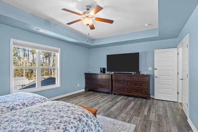 bedroom featuring a raised ceiling, hardwood / wood-style floors, and ceiling fan