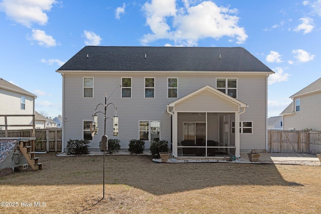 back of property with a yard, a patio area, and a sunroom