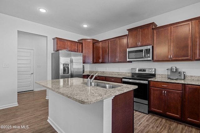 kitchen featuring sink, a center island with sink, dark hardwood / wood-style floors, stainless steel appliances, and light stone countertops