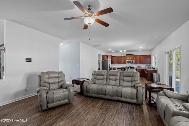 living room with dark hardwood / wood-style flooring and ceiling fan with notable chandelier