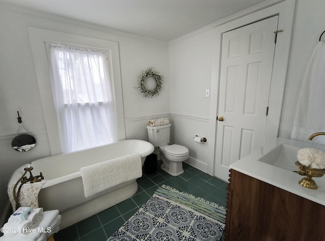 bathroom with a tub to relax in, vanity, toilet, crown molding, and tile patterned floors