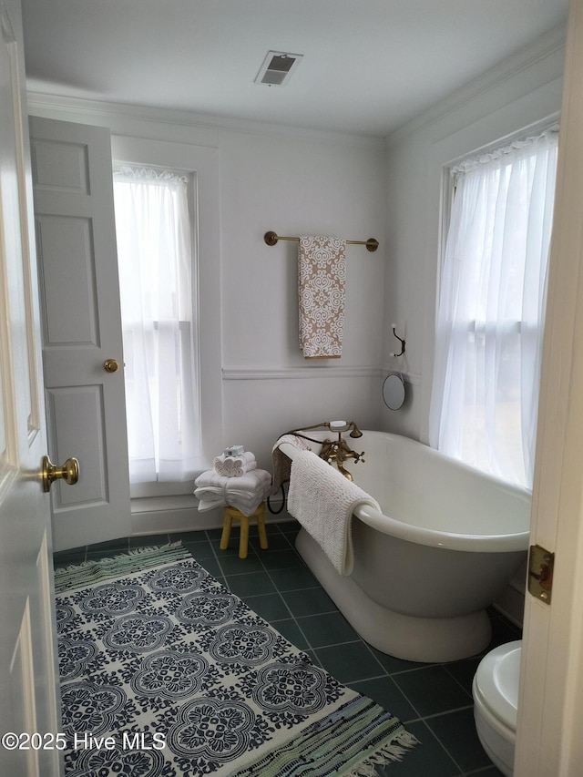 bathroom featuring tile patterned flooring, ornamental molding, and a bathing tub