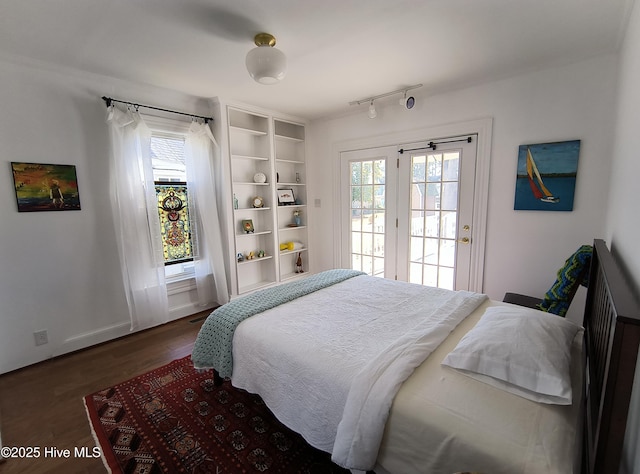 bedroom featuring track lighting, access to exterior, and dark hardwood / wood-style flooring