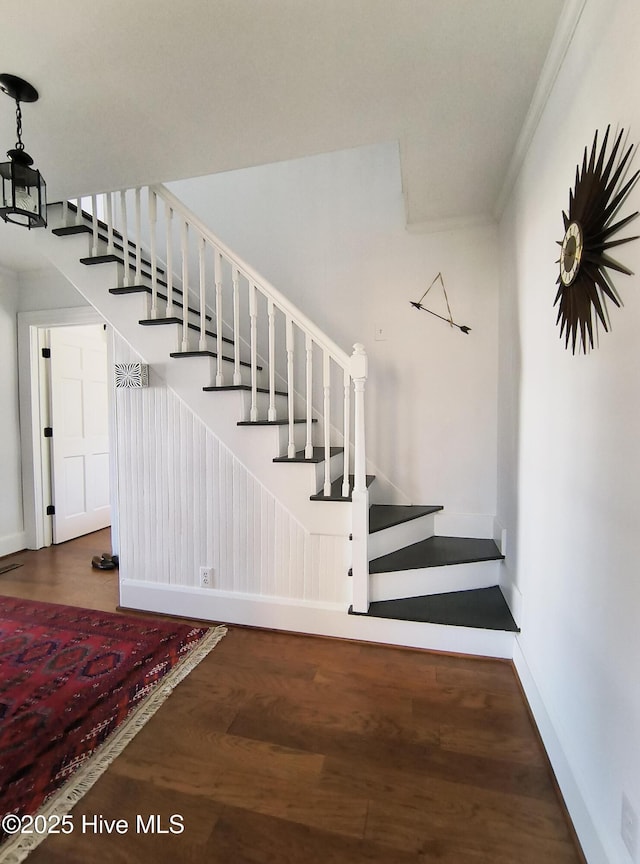 stairway with crown molding and wood-type flooring