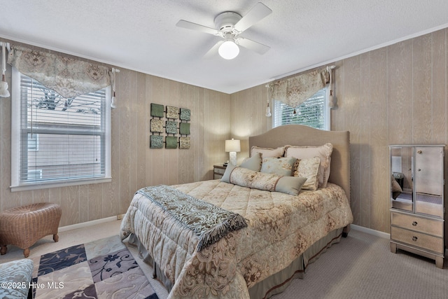 carpeted bedroom featuring crown molding, ceiling fan, a textured ceiling, and wood walls