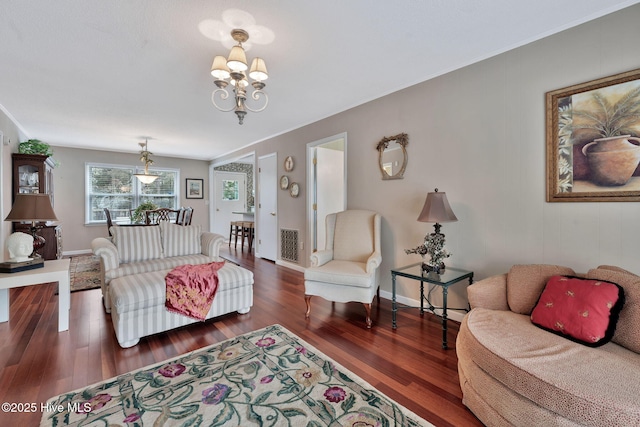 living room featuring crown molding, dark hardwood / wood-style floors, and an inviting chandelier