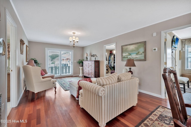 living room with dark hardwood / wood-style flooring, crown molding, and a chandelier