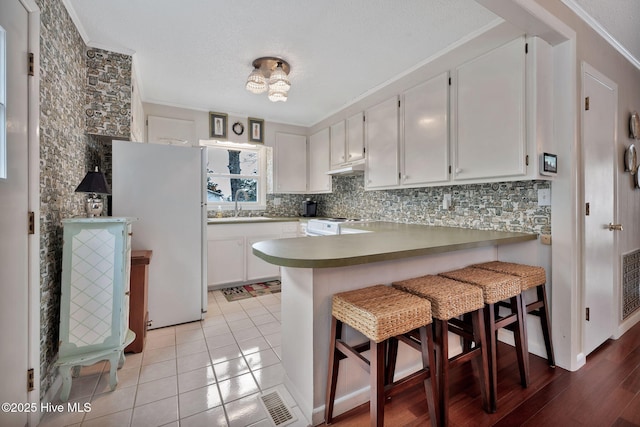 kitchen featuring sink, kitchen peninsula, white cabinets, white appliances, and backsplash