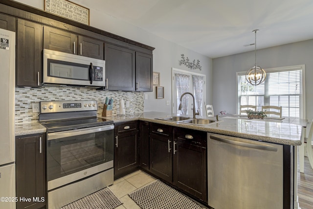 kitchen featuring sink, kitchen peninsula, stainless steel appliances, and decorative backsplash