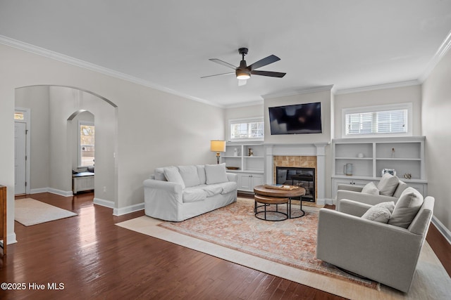 living room with ornamental molding, a healthy amount of sunlight, dark hardwood / wood-style flooring, and a tiled fireplace