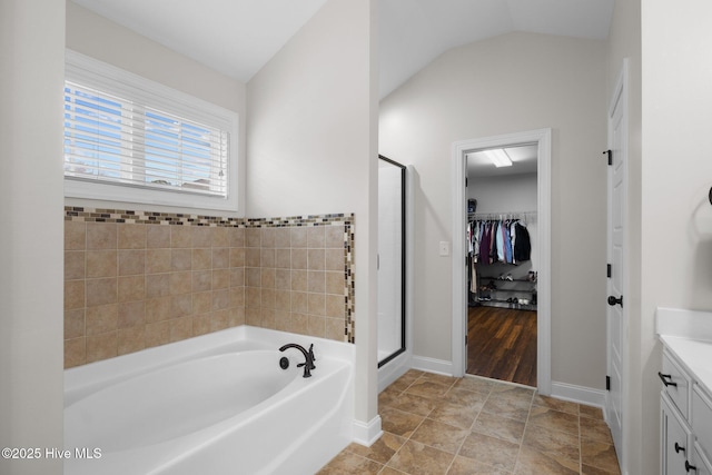 bathroom featuring vaulted ceiling, shower with separate bathtub, vanity, and tile patterned floors