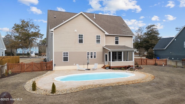 rear view of property with a sunroom, a fenced in pool, and a patio area