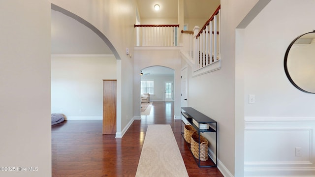 foyer entrance with ornamental molding, dark wood-type flooring, and a towering ceiling