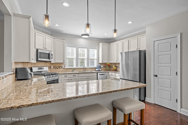 kitchen featuring appliances with stainless steel finishes, sink, white cabinets, ornamental molding, and kitchen peninsula