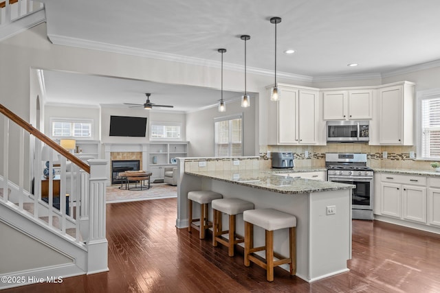 kitchen with stainless steel appliances, white cabinetry, a kitchen bar, and decorative light fixtures