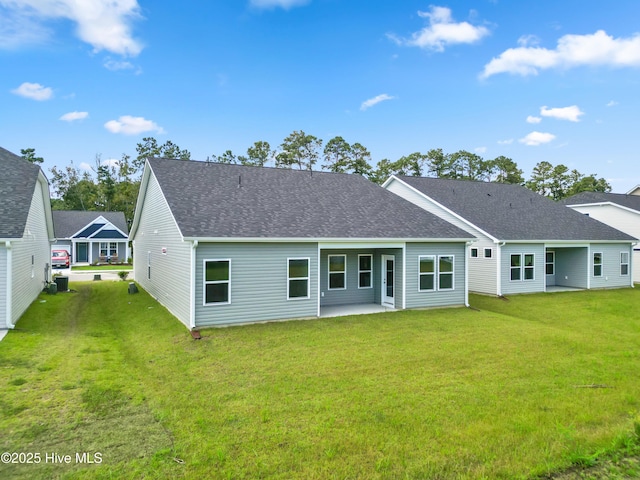 rear view of property featuring a patio area, a shingled roof, and a yard