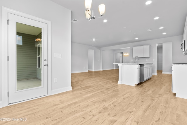 kitchen with a notable chandelier, white cabinetry, open floor plan, light countertops, and light wood-type flooring