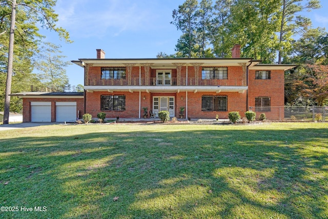 view of front facade featuring a garage, a balcony, and a front yard