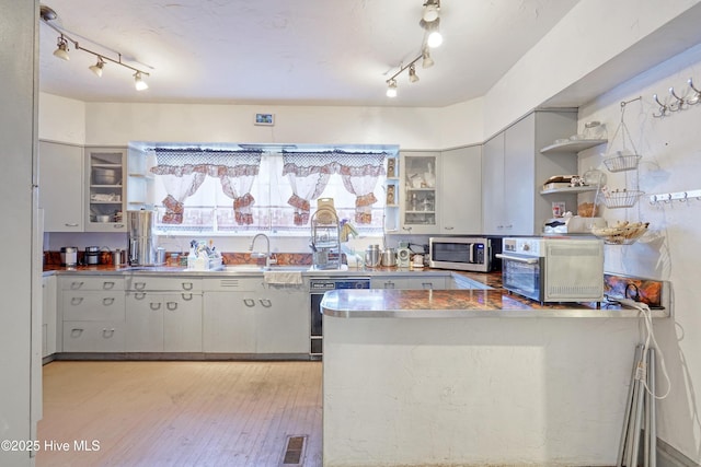 kitchen with sink, light hardwood / wood-style floors, kitchen peninsula, and dishwasher