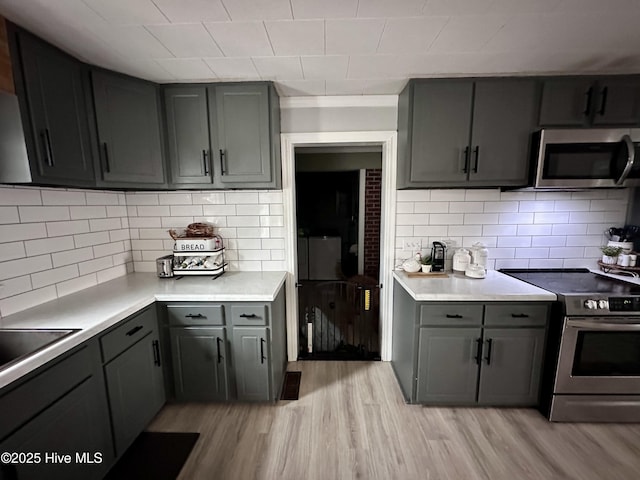 kitchen with light hardwood / wood-style flooring, decorative backsplash, gray cabinets, and stainless steel appliances