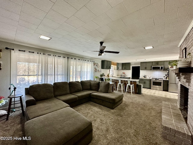 living room with ornamental molding, carpet flooring, ceiling fan, and a fireplace