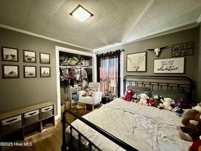 bedroom with ornamental molding, wood-type flooring, and a closet