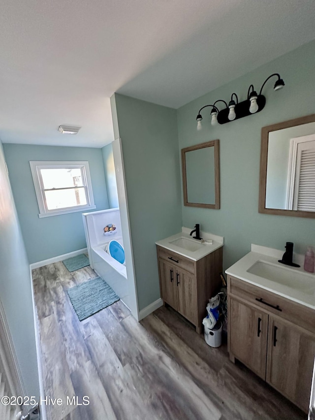 bathroom with vanity, a bathtub, and wood-type flooring