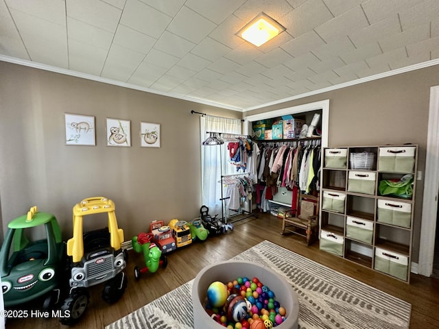 recreation room with ornamental molding and dark hardwood / wood-style floors