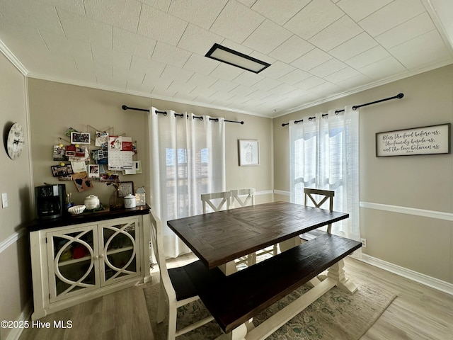 dining room with ornamental molding and light wood-type flooring