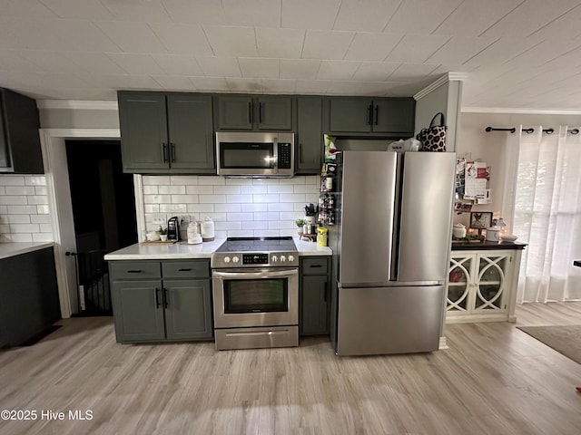 kitchen featuring backsplash, crown molding, light hardwood / wood-style floors, and appliances with stainless steel finishes