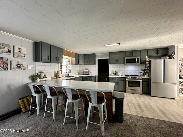 kitchen featuring stainless steel appliances, sink, a breakfast bar area, and kitchen peninsula