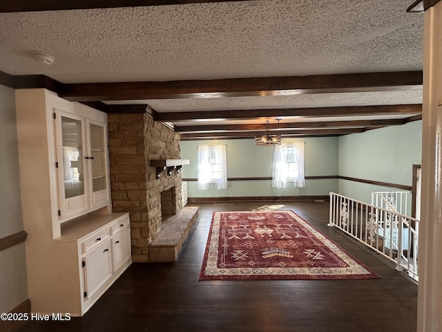 hall featuring a textured ceiling, dark wood-style flooring, beam ceiling, and baseboards