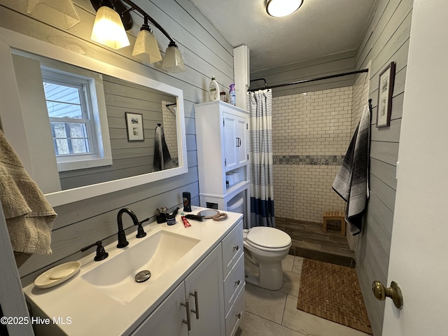 bathroom featuring wooden walls, a tile shower, and vanity