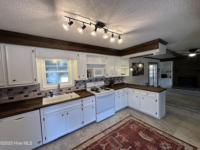 kitchen with hanging light fixtures, white appliances, a sink, and white cabinetry