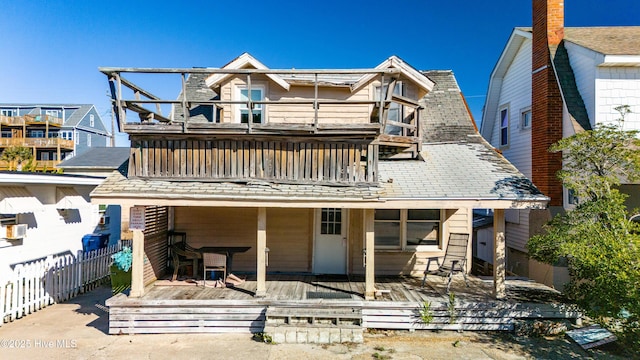 rear view of property featuring a balcony and a deck