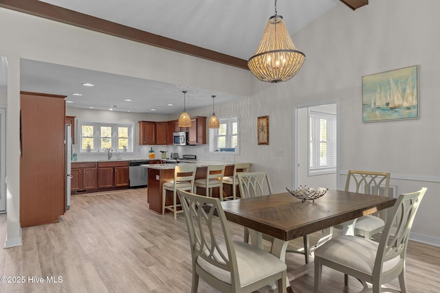 dining space featuring sink, a chandelier, light hardwood / wood-style floors, and vaulted ceiling with beams